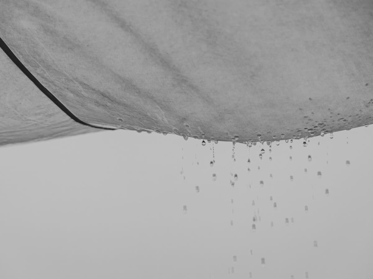 Plumber repairing a burst pipe through a ceiling opening